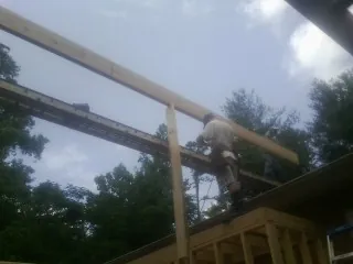 Carpenter setting a ridge beam over a new addition frame — Ice Dam Removal by Roofing Brothers in Caret