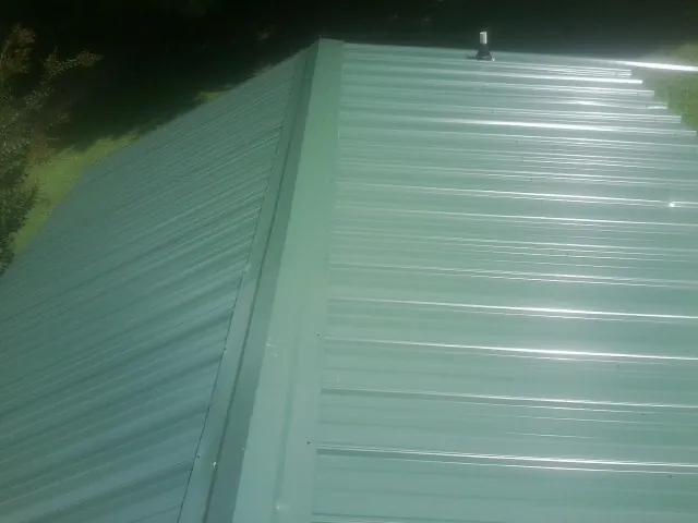New green metal panels meeting at the ridge of a roof — Flat Roof Repair work by our crew in Caret