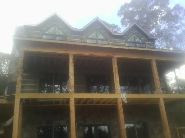 Dormers and porch framing on a large log home under construction — Roof Coating work by our crew in Caret