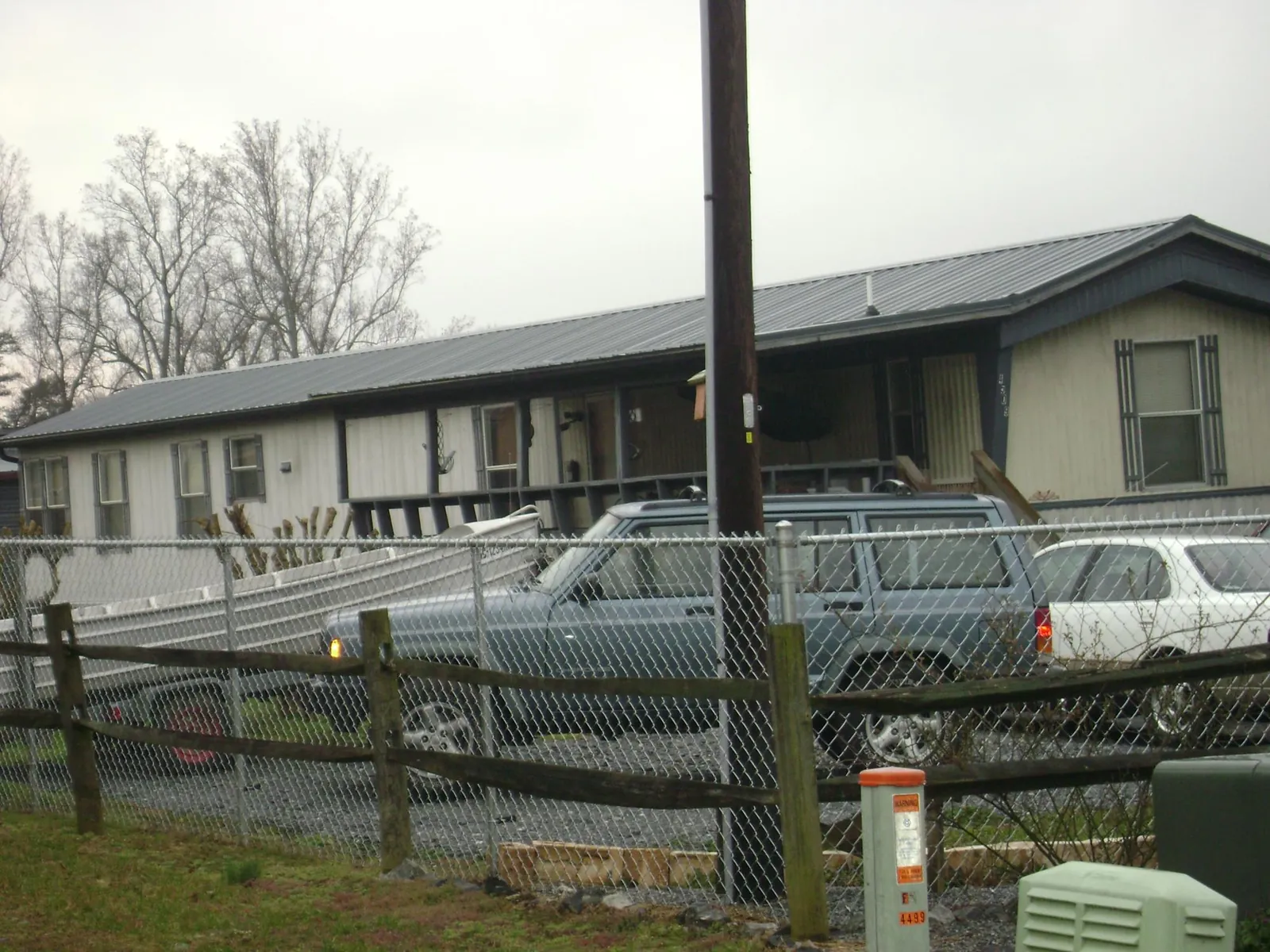 Dark metal roof on a long single story building behind a chain link fence in Caret