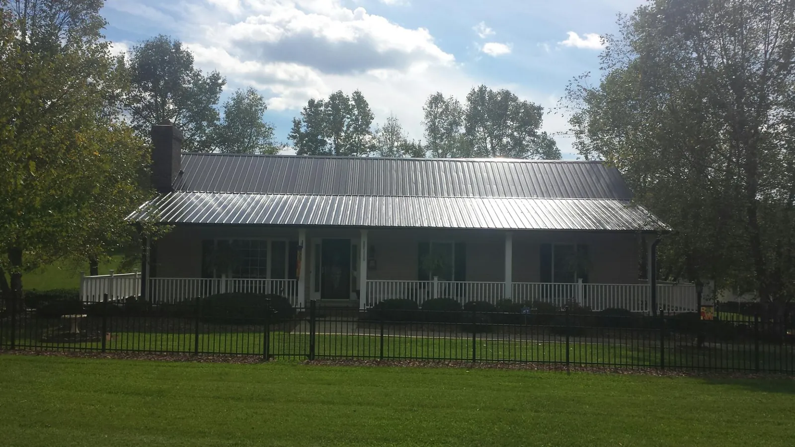 Gray metal roof on a brick ranch with a full width front porch — Gutter Guard Installation work by our crew in Caret