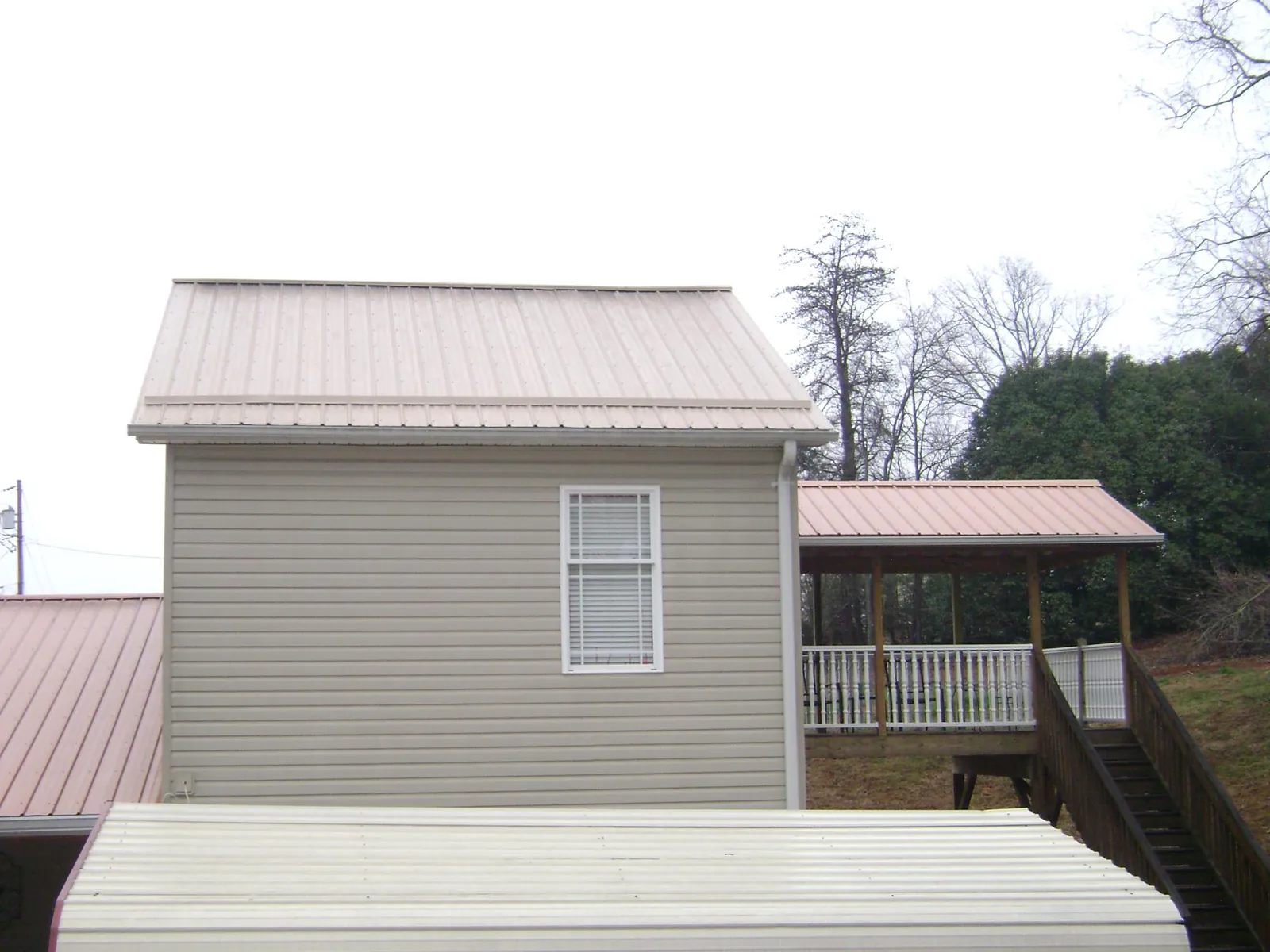 Tan metal roofs on a two story addition and attached porch, from a Roof Replacement job in Caret